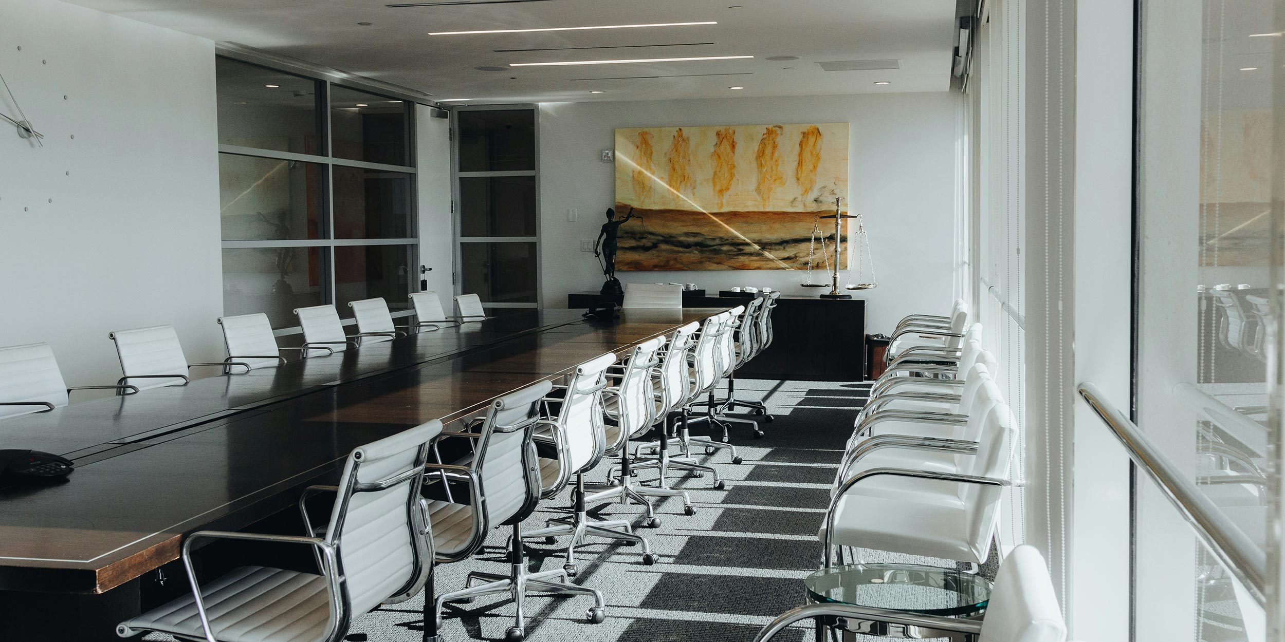 A bright, sleek conference room with a long table surrounded by modern white chairs.
