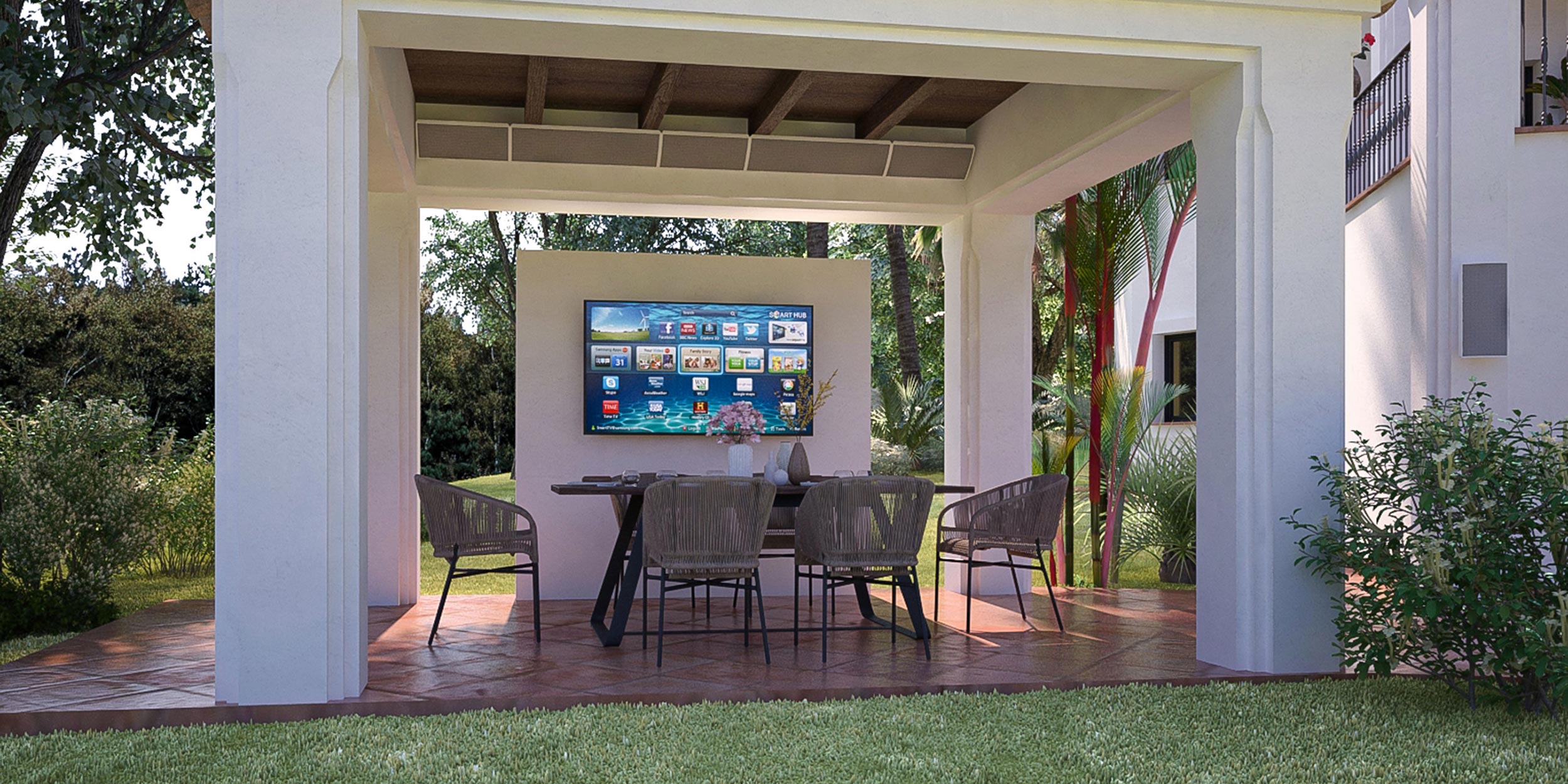 An outdoor seating area under a shaded structure with a large TV mounted on the wall.