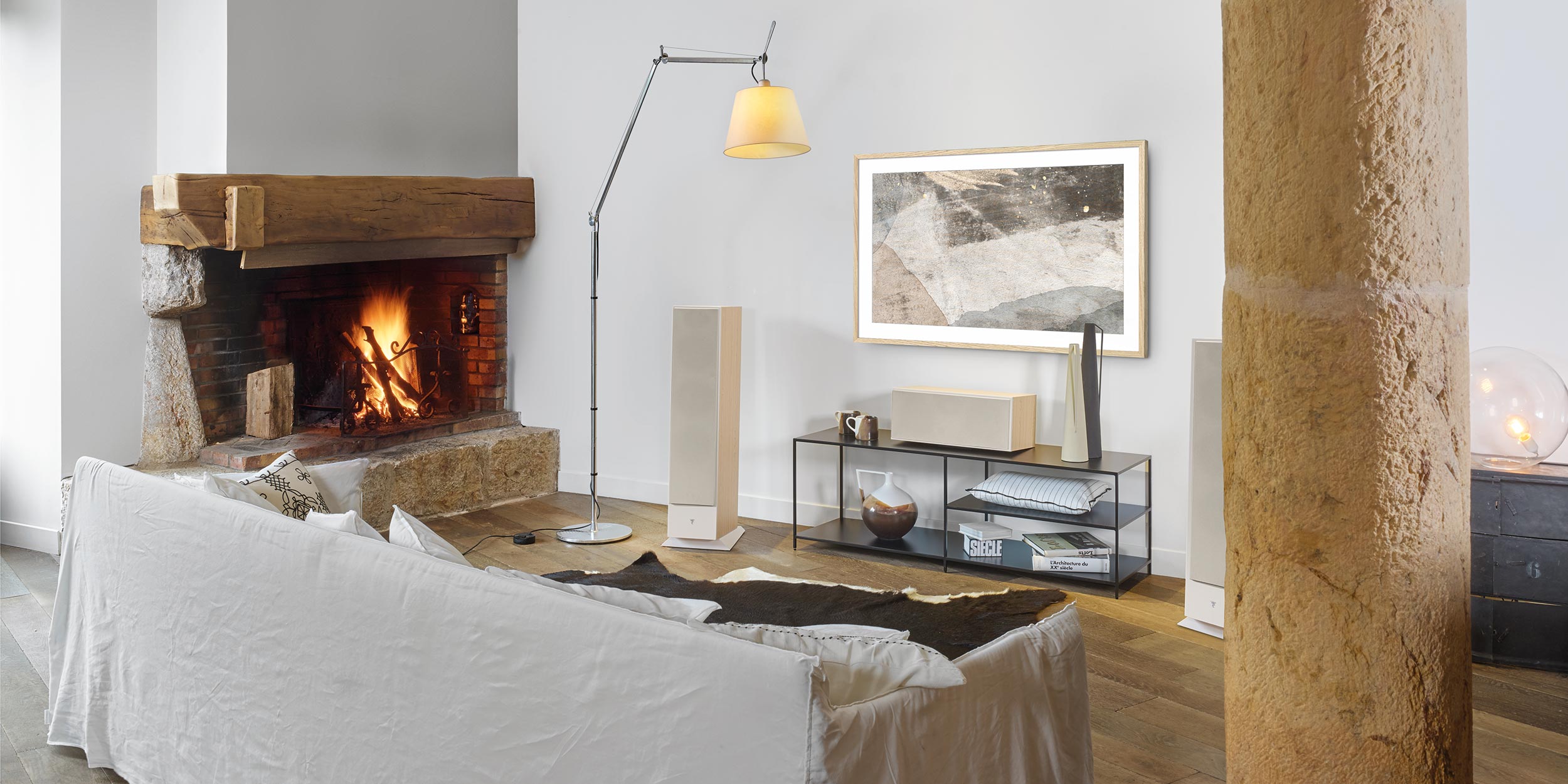 A living room with a warm fireplace, modern furniture, and a large framed TV on the wall.