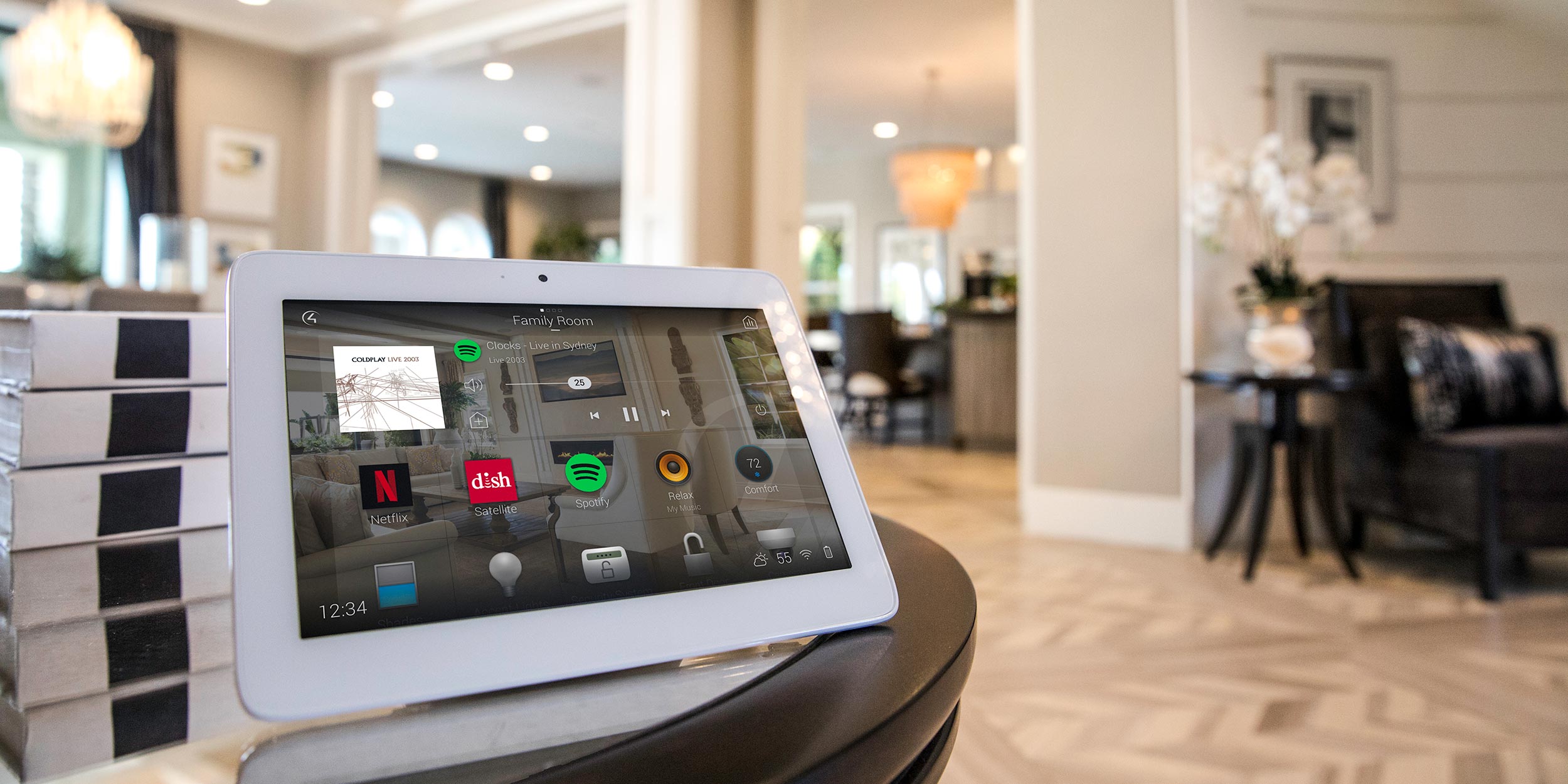 A tablet placed on a table in a modern home, displaying various smart home controls.